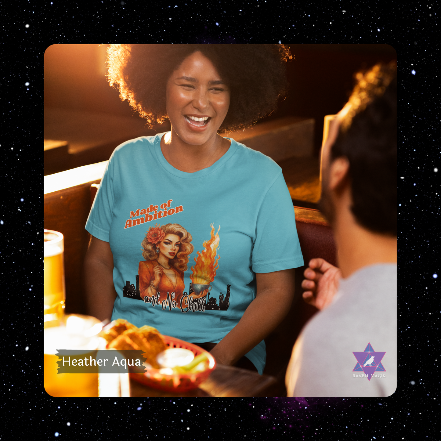Woman wearing a blue t-shirt with a graphic design, sitting at a table with food and a drink. Aries Archetype T-shirt with “Made of Ambition and No Chill” slogan, styled for bold, driven energy and trailblazing spirits.