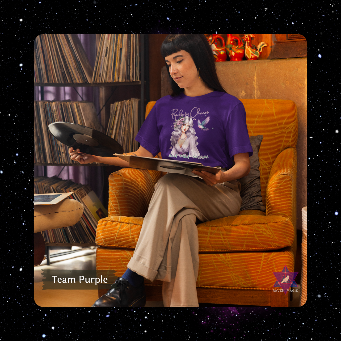 Person sitting on an orange chair wearing a purple t-shirt with a graphic design, holding a book. Libra Archetype T-shirt with “Radiates Charm and Mild Chaos” slogan, styled for magnetic, indecisive energy and aesthetic flair.