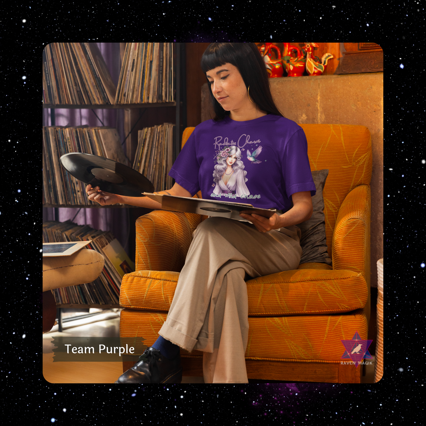 Person sitting in an armchair holding a vinyl record, wearing a purple t-shirt with a graphic design. Libra Zodiac T-shirt with “Radiates Charm and Mild Chaos” slogan, styled for magnetic, balanced energy.