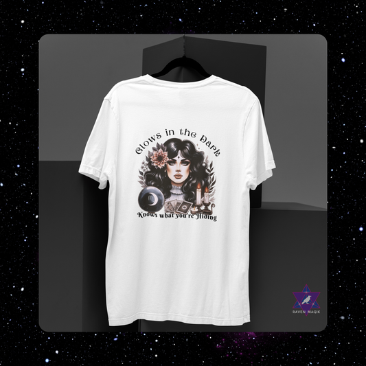 White t-shirt with graphic design on a black background. Scorpio Zodiac T-shirt with “Glows in the Dark and Knows What You’re Hiding” slogan, styled for intense, psychic energy.